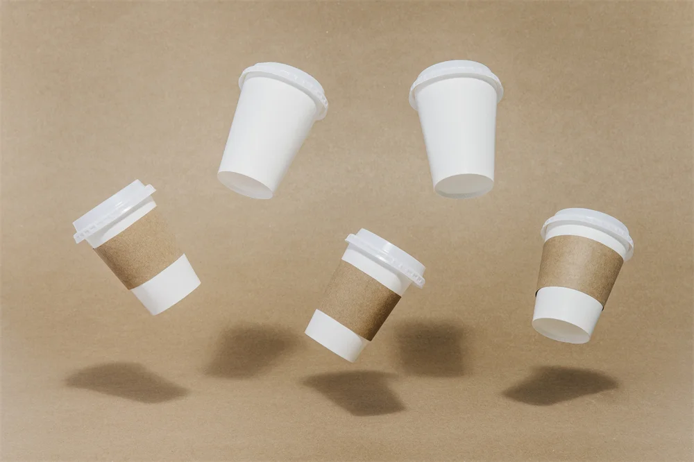 How to Measure for Custom Cup Sleeves? blog cover: Floating white coffee cups, some with brown paper sleeves, against a brown background.